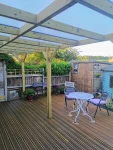 Pergola on decking with sheds in garden